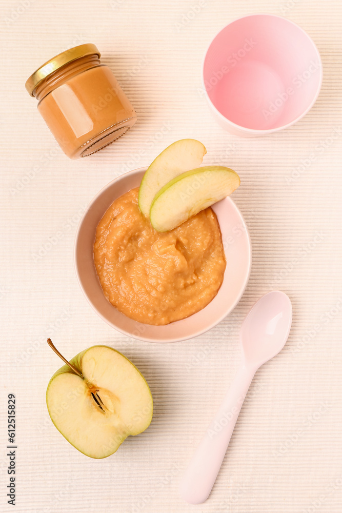 Bowl of apple baby puree on light background