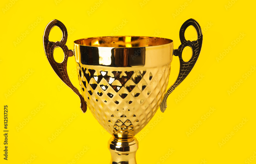 Gold cup on yellow background, closeup