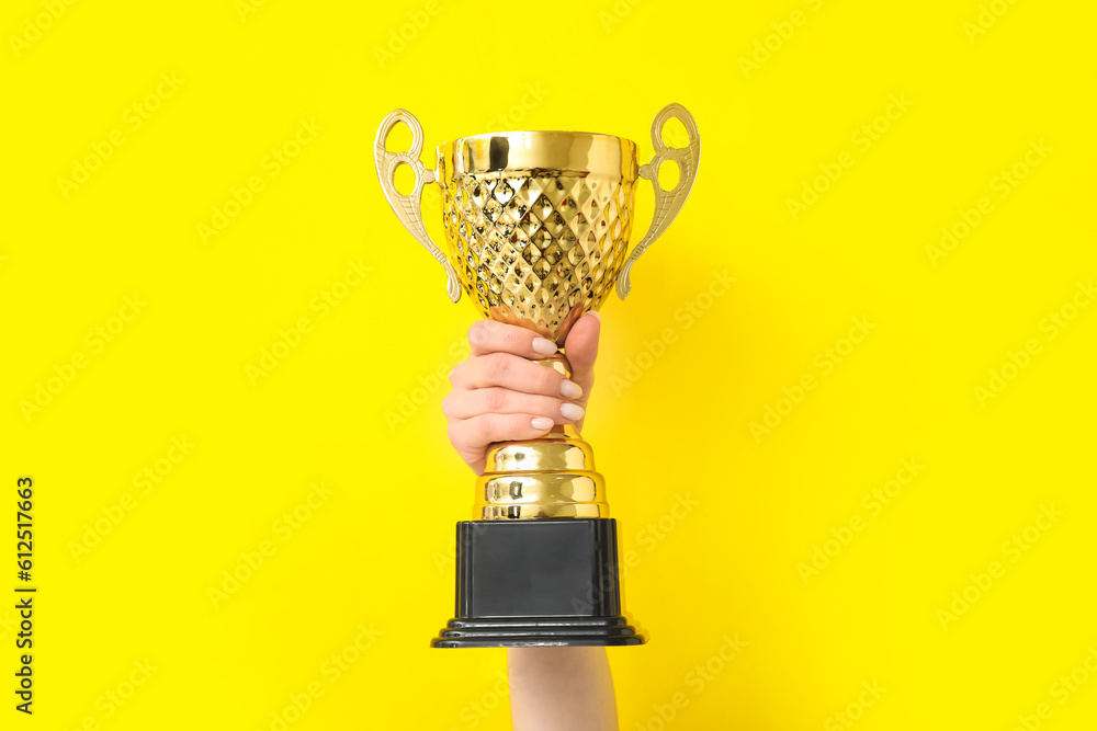 Woman with gold cup on yellow background