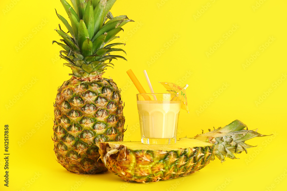 Glass of tasty pineapple smoothie, straw and umbrella on yellow background