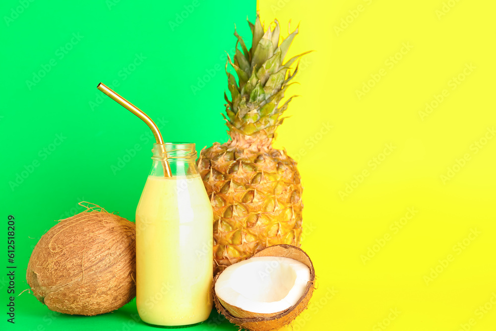 Glass bottle of tasty pineapple smoothie, straw and coconut on color background