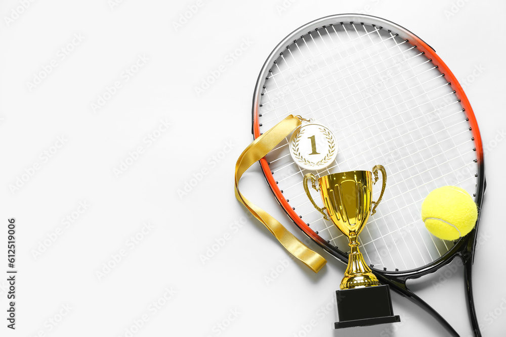 Gold cup with first place medal, tennis racket and ball on light background