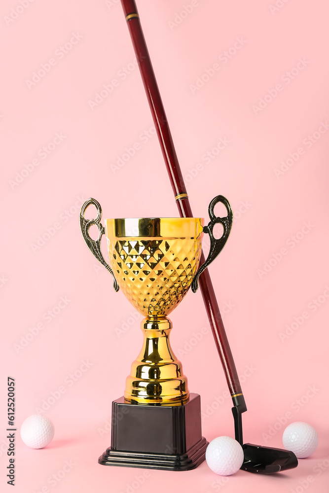 Gold cup with golf club and balls on pink background