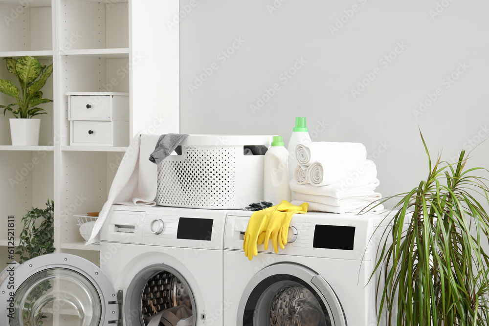 Basket with detergents and towels on washing machines in laundry room