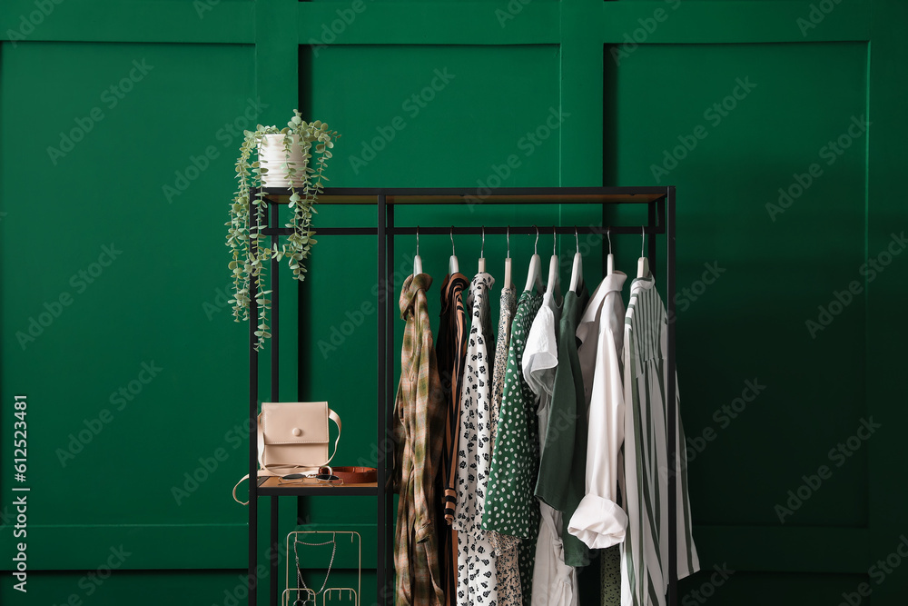 Shelving unit with clothes and accessories near green wall