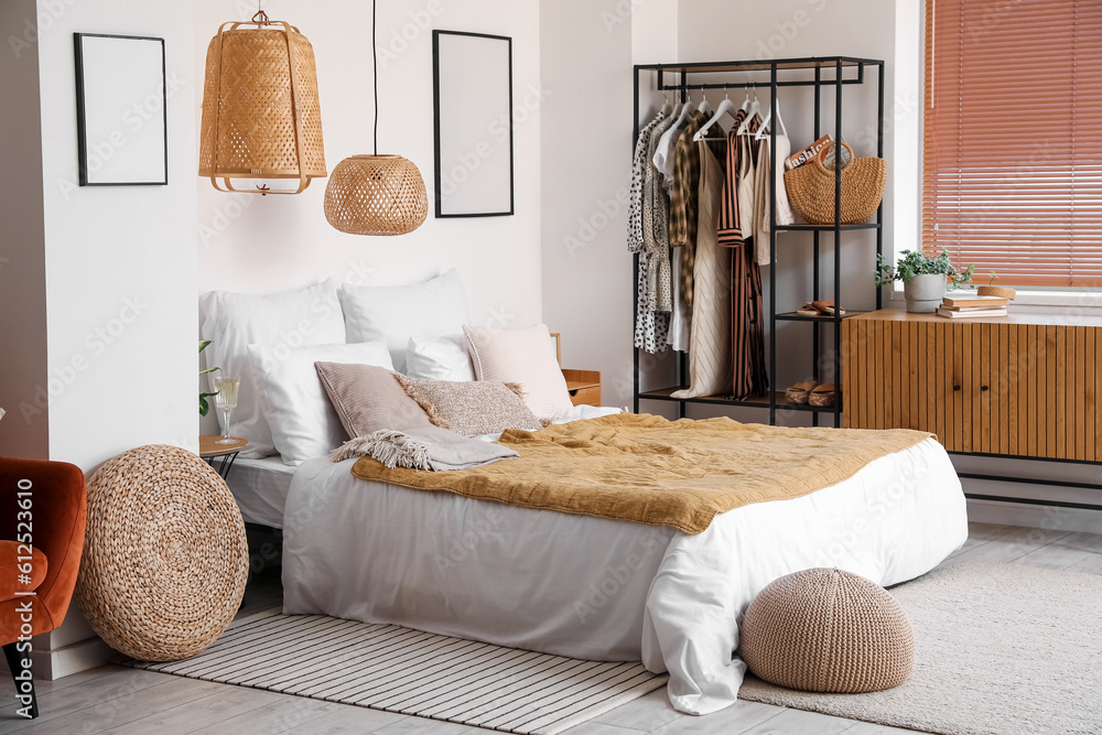 Interior of light bedroom with shelving unit and clothes