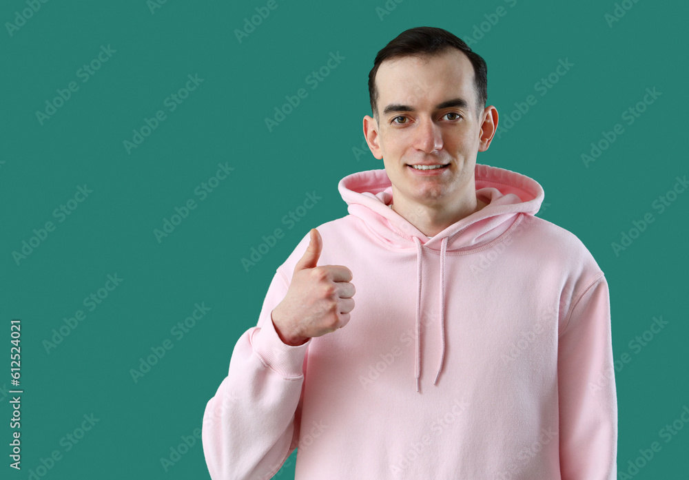 Young man showing thumb-up on green background