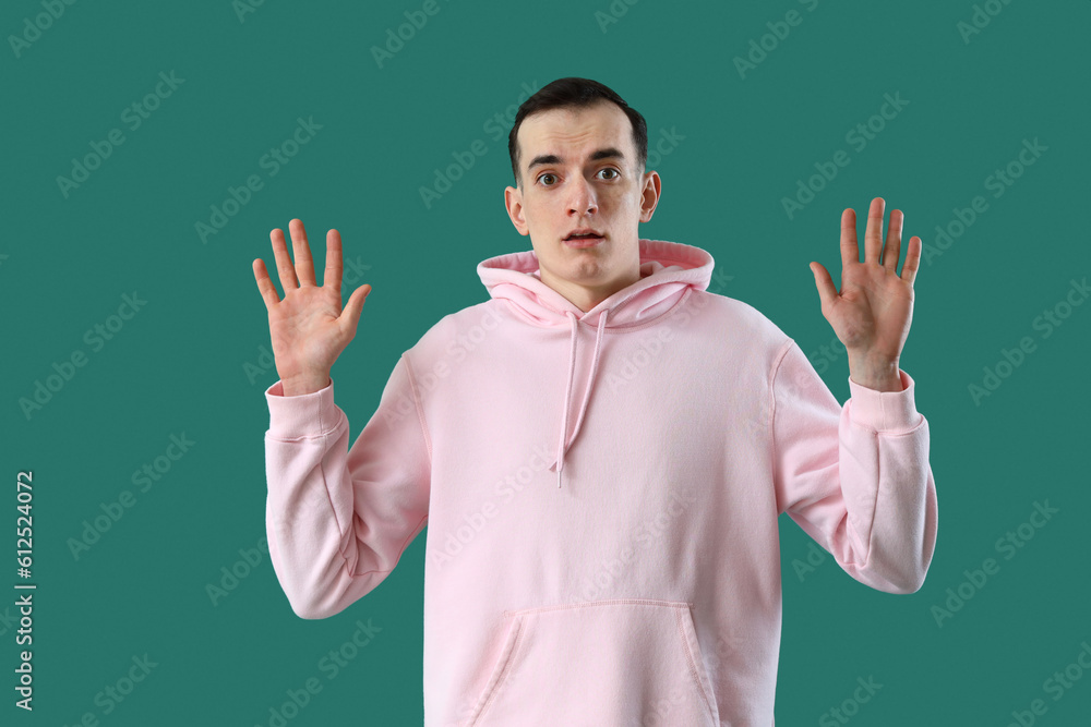 Scared young man showing hands on green background