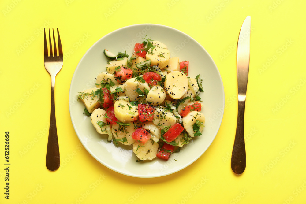 Plate of tasty Potato Salad with vegetables on yellow background