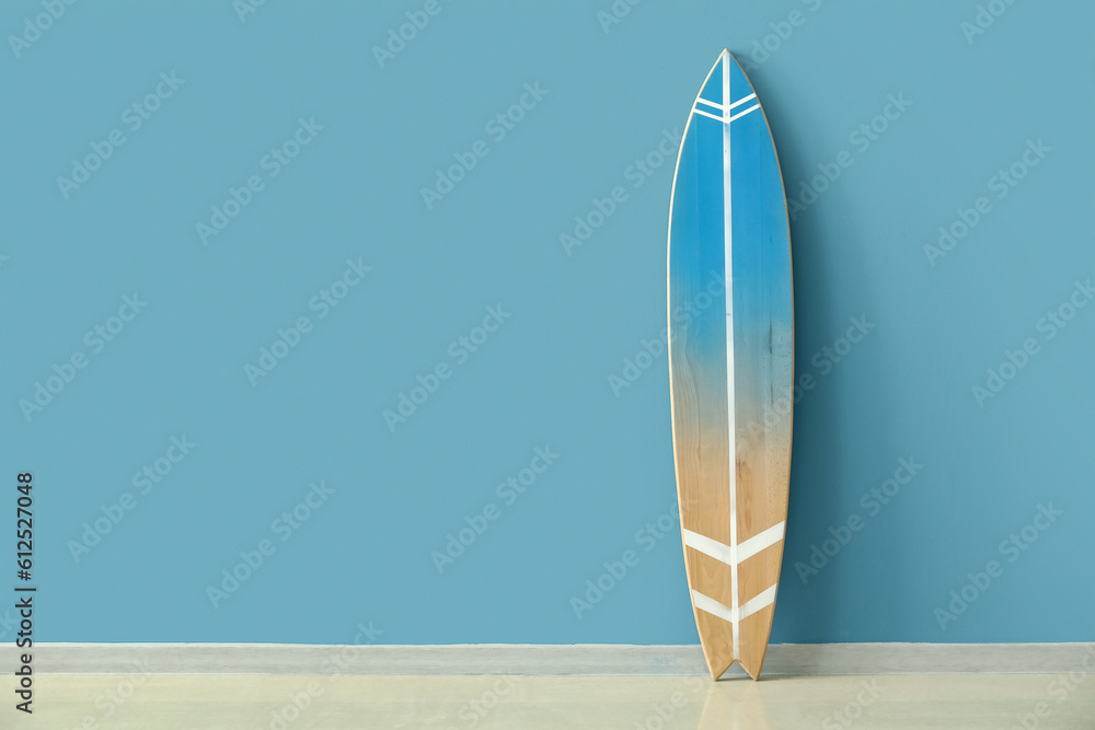 Wooden surfboard near blue wall