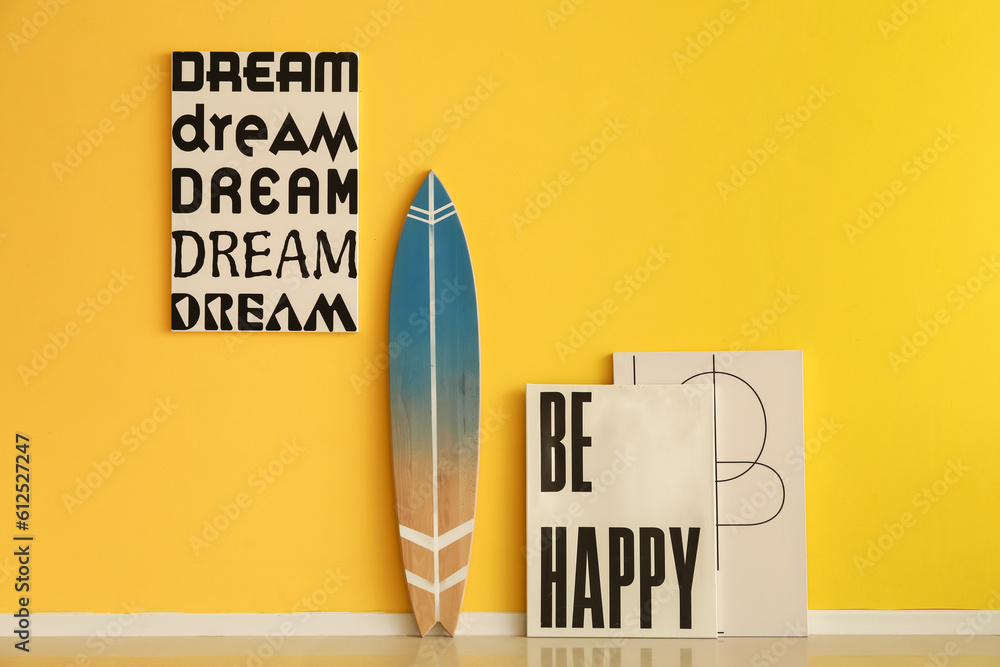 Surfboard with posters near yellow wall in room