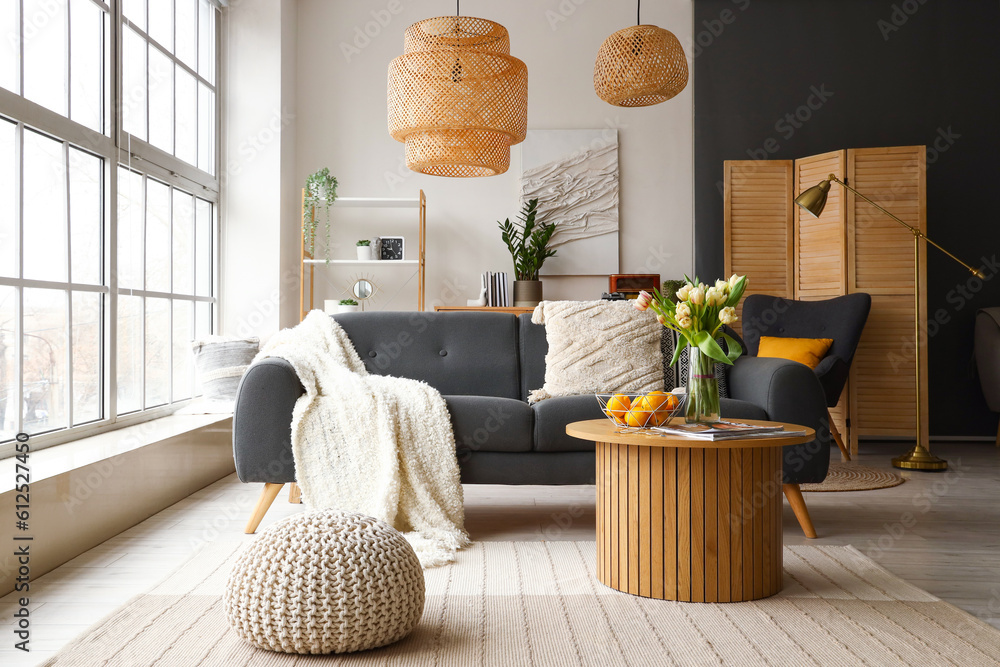 Interior of stylish living room with cozy sofa and coffee table near big window