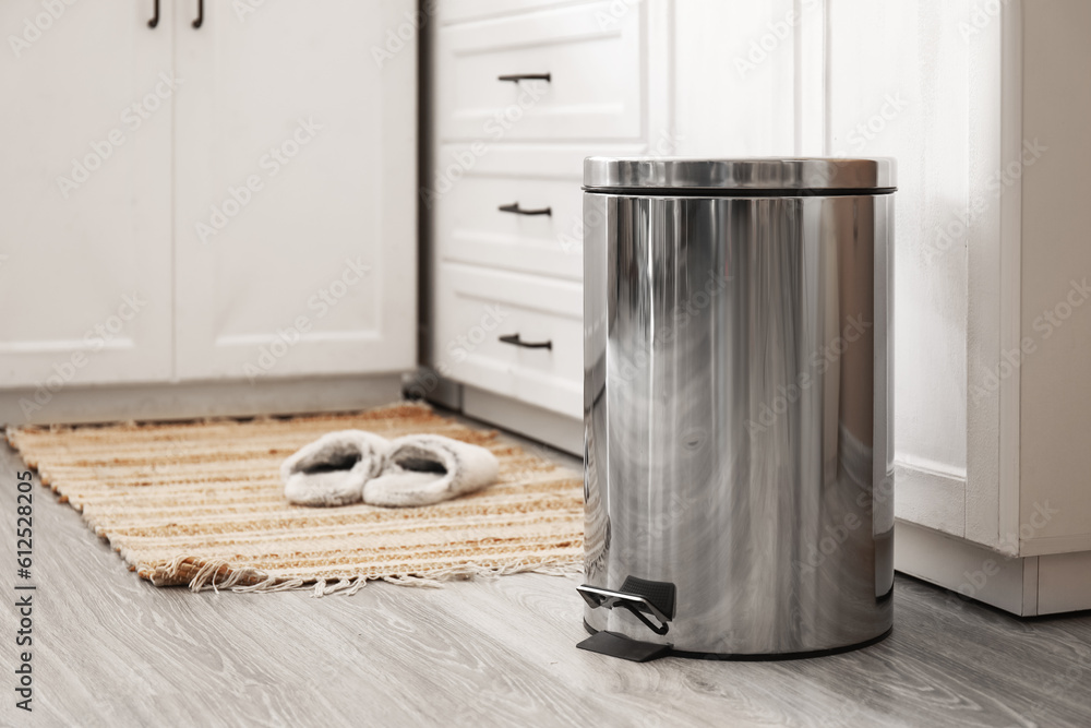 Metallic trash bin on floor in modern kitchen