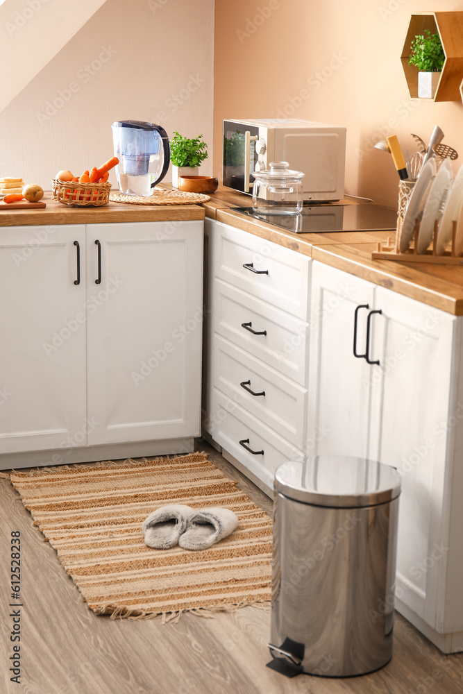 Metallic trash bin on floor in modern kitchen