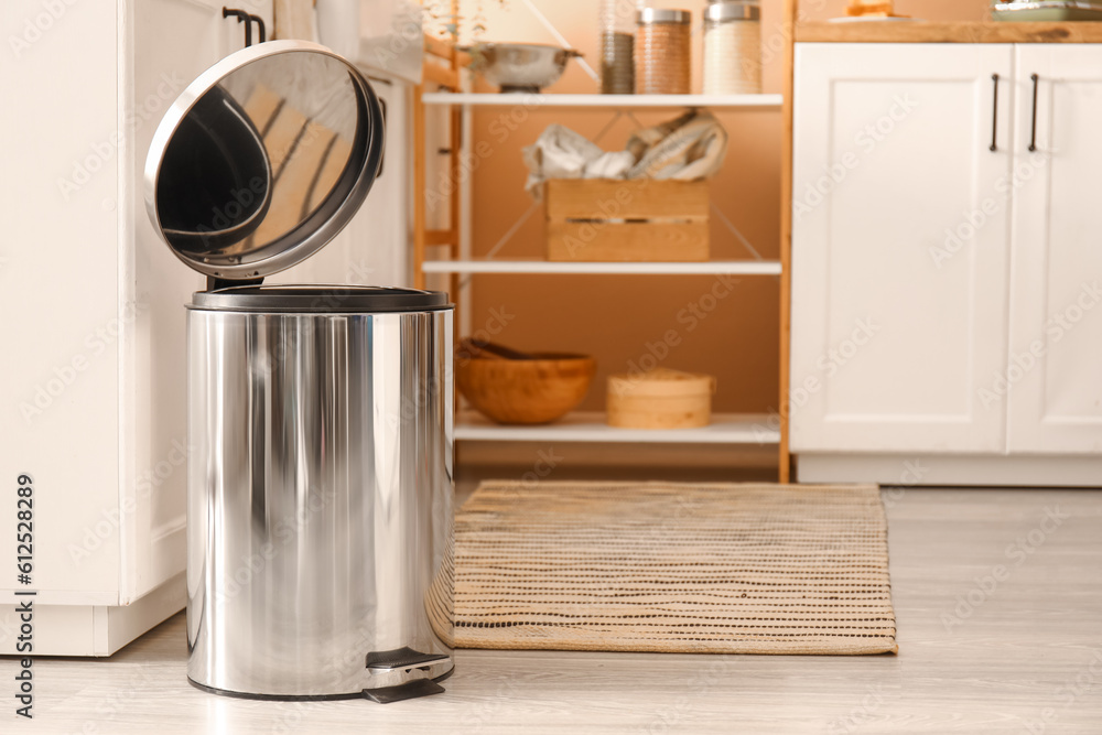 Opened metallic trash bin on floor in modern kitchen