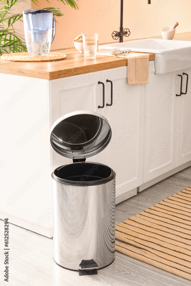 Opened metallic trash bin on floor in modern kitchen