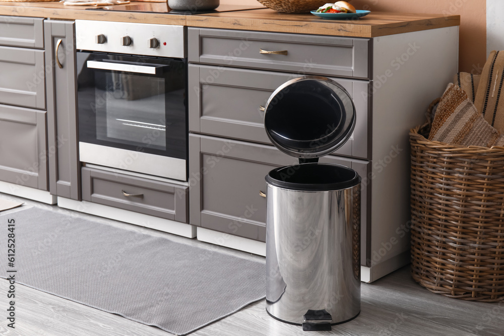 Opened metallic trash bin on floor in modern kitchen