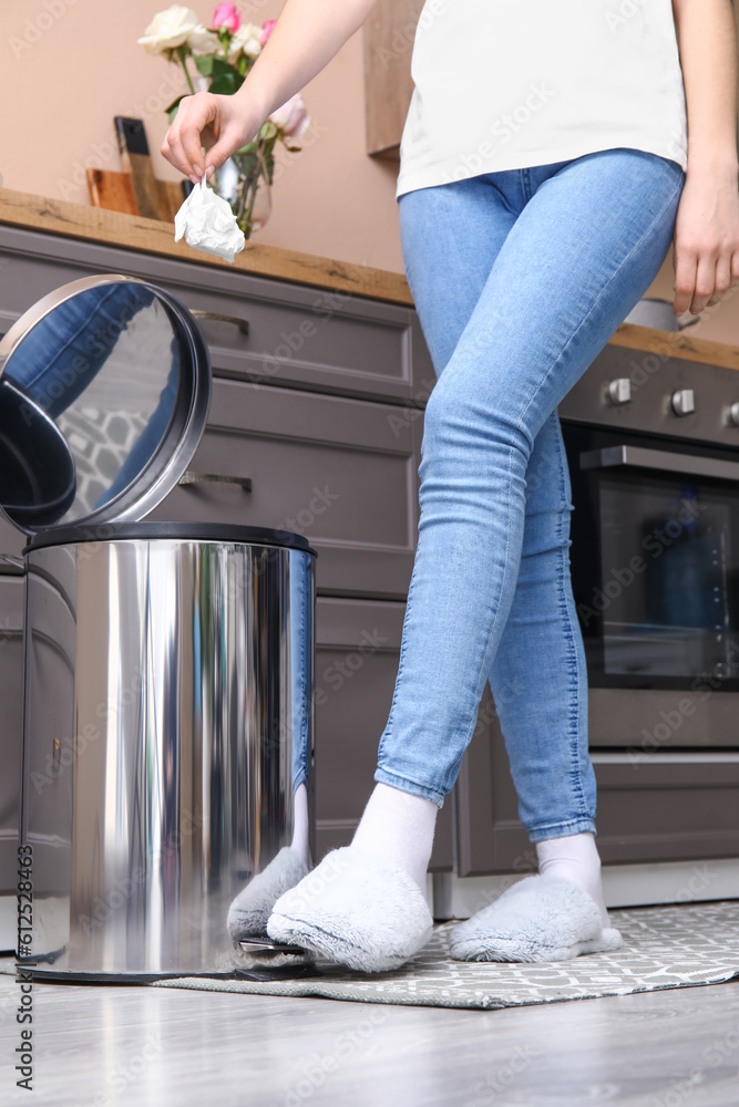 Woman throwing rubbish into trash been in modern kitchen