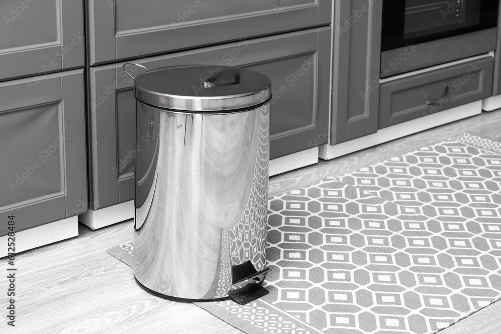 Metallic trash bin on floor in modern kitchen