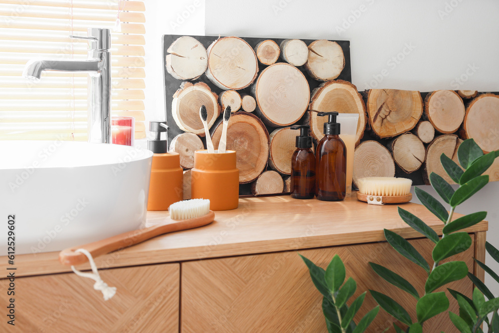 Sink with bath accessories on table near window in room