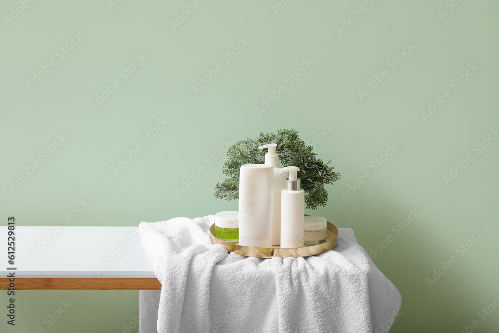 Tray with bath accessories and bonsai on table near green wall