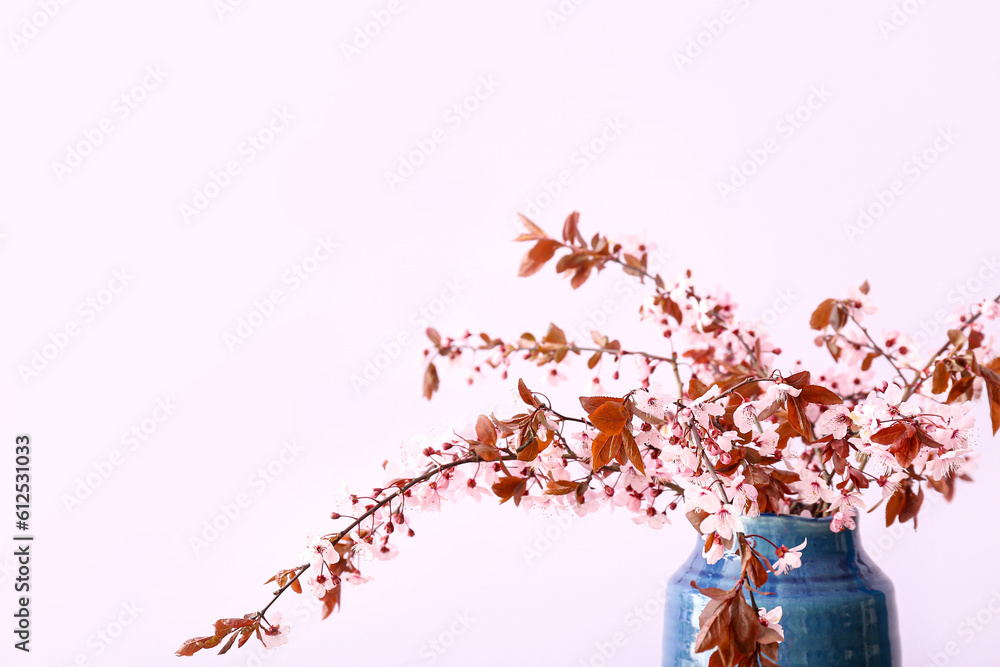 Vase with blooming tree branches on pink background