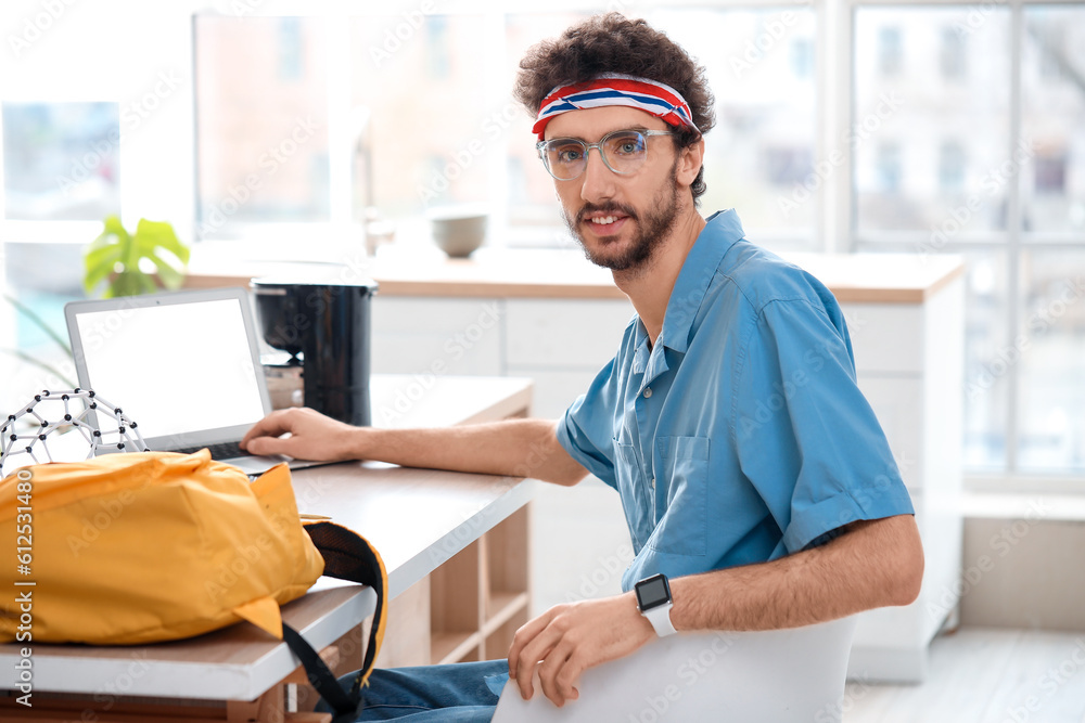 Male student studying with laptop at table in kitchen