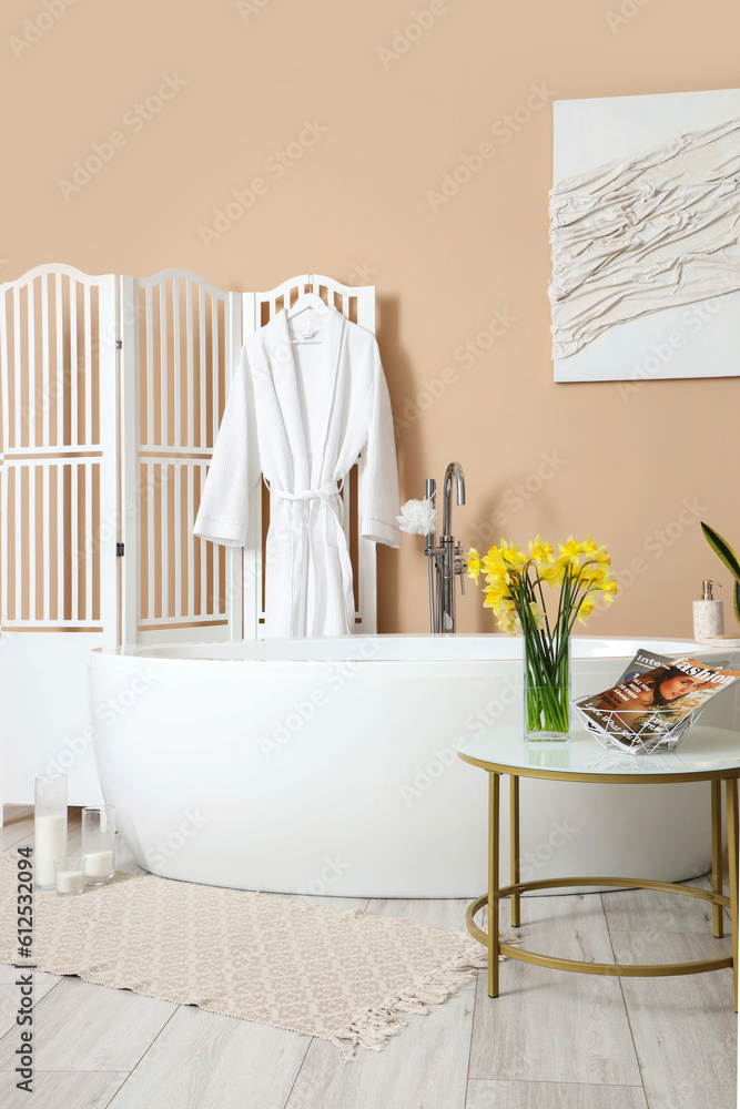 Interior of bathroom with bathtub and narcissus flowers on table