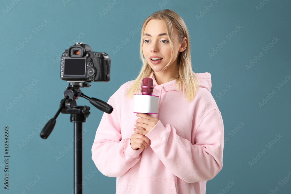 Female journalist with microphone recording video on blue background