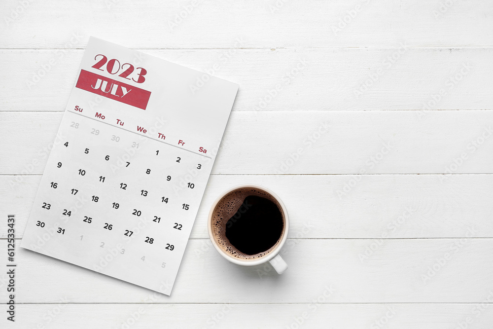 Calendar and cup of coffee on white wooden background