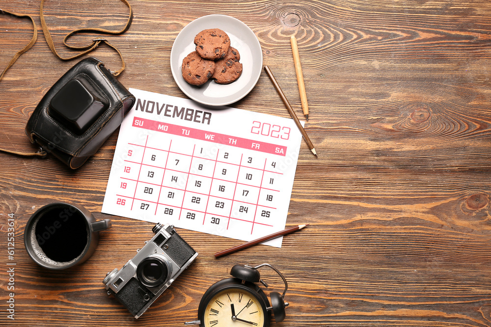 Composition with calendar, photo camera, cup of coffee and cookies on wooden background