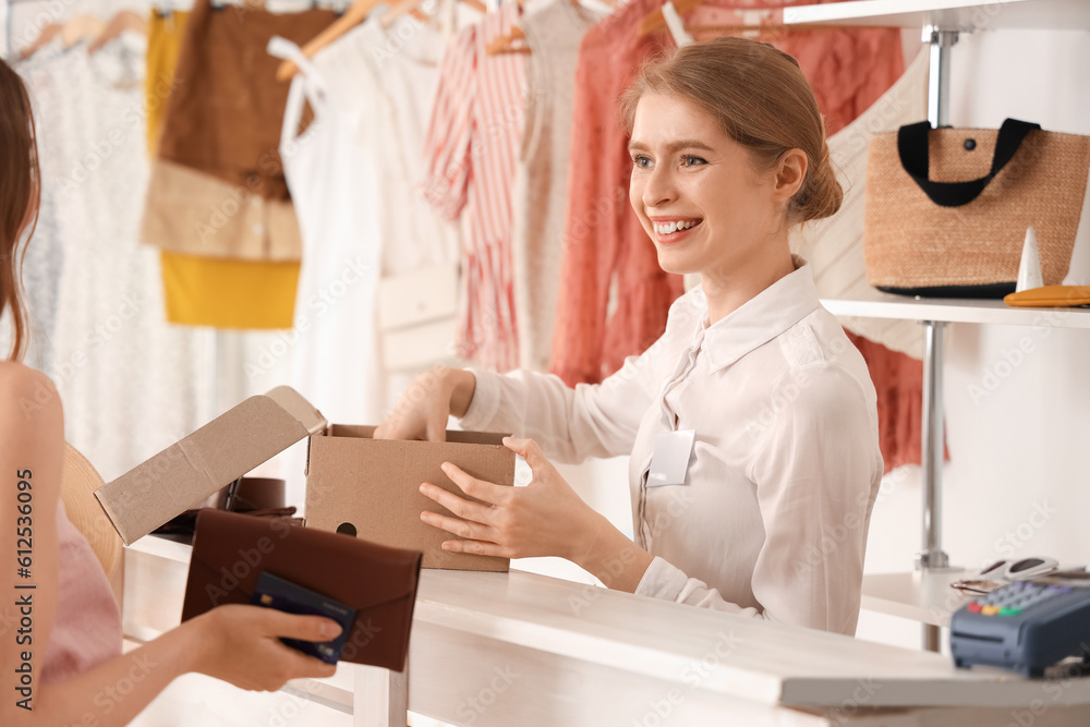 Female sales assistant selling shoes to customer in boutique