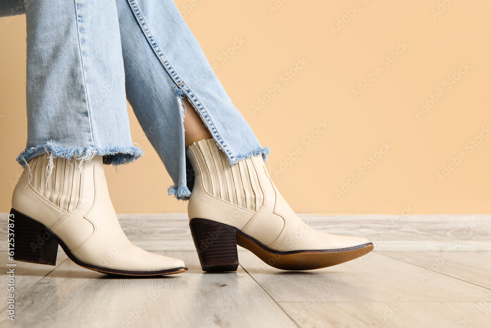 Female legs in stylish shoes near color wall, closeup