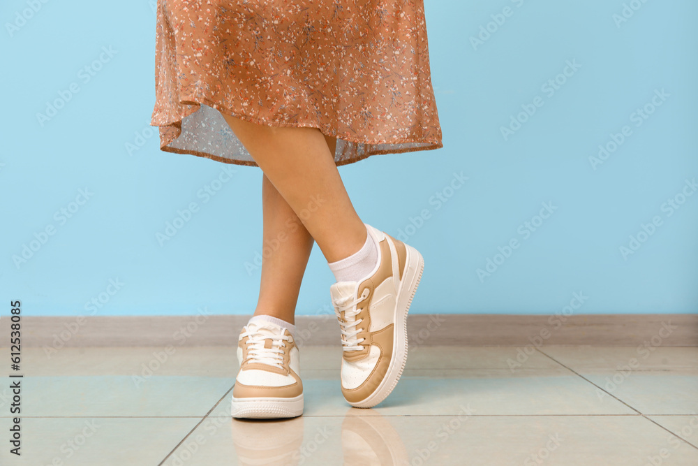 Woman in stylish sneakers against color wall