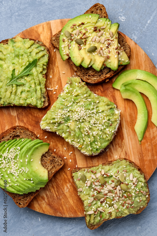 Board of tasty avocado toasts on grey background