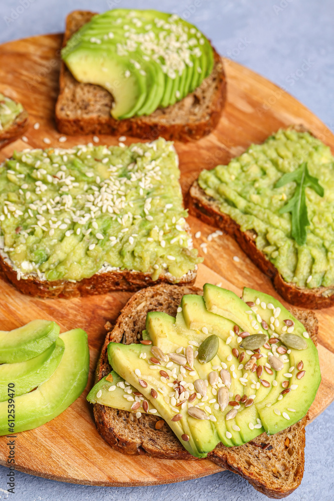 Board of tasty avocado toasts on grey background, closeup