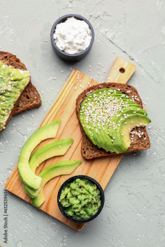 Wooden board of tasty avocado toast on light background