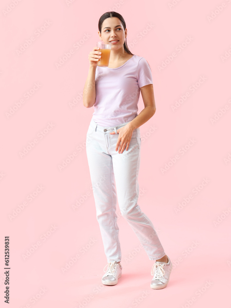 Young woman with glass of vegetable juice on pink background