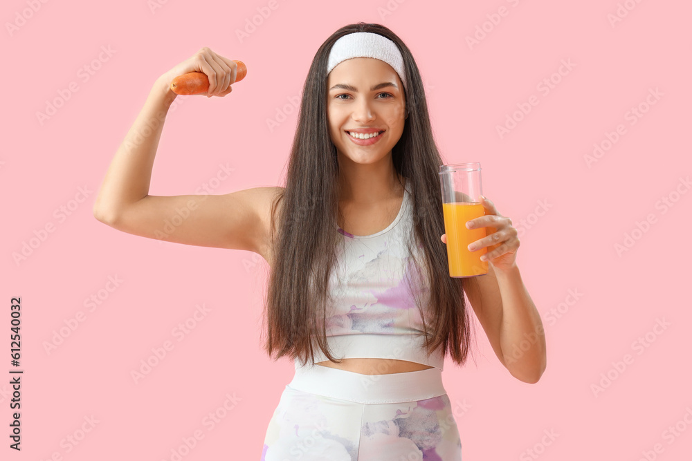 Sporty young woman with glass of vegetable juice and carrot on pink background