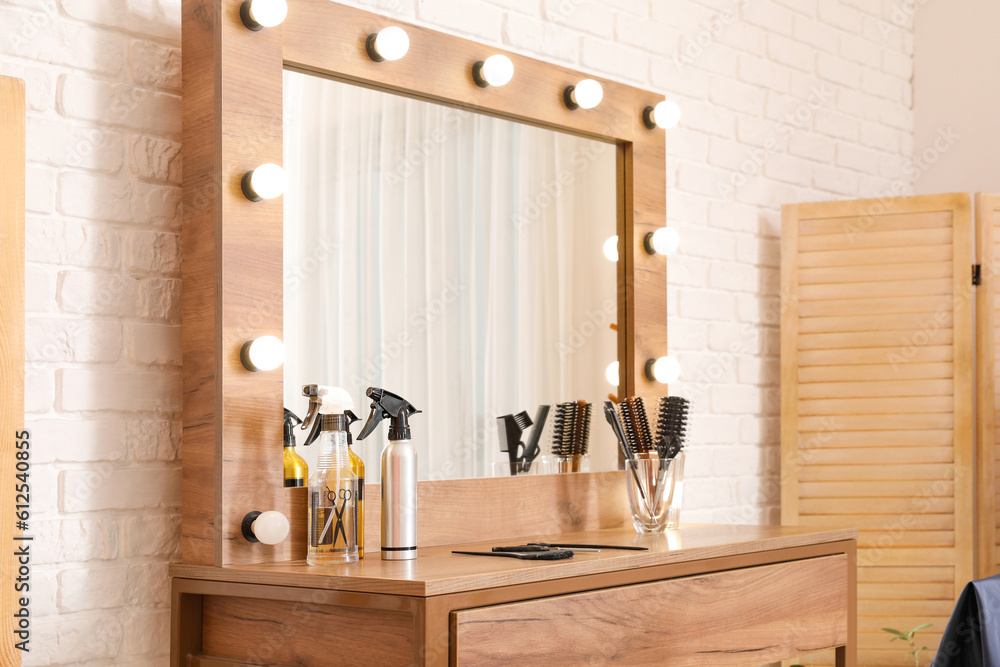 Different hairdressing tools on table near light brick wall in salon