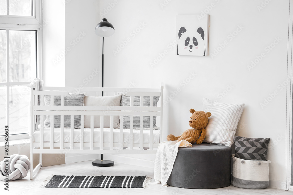 Stylish interior of childrens room  with baby bed and ottoman