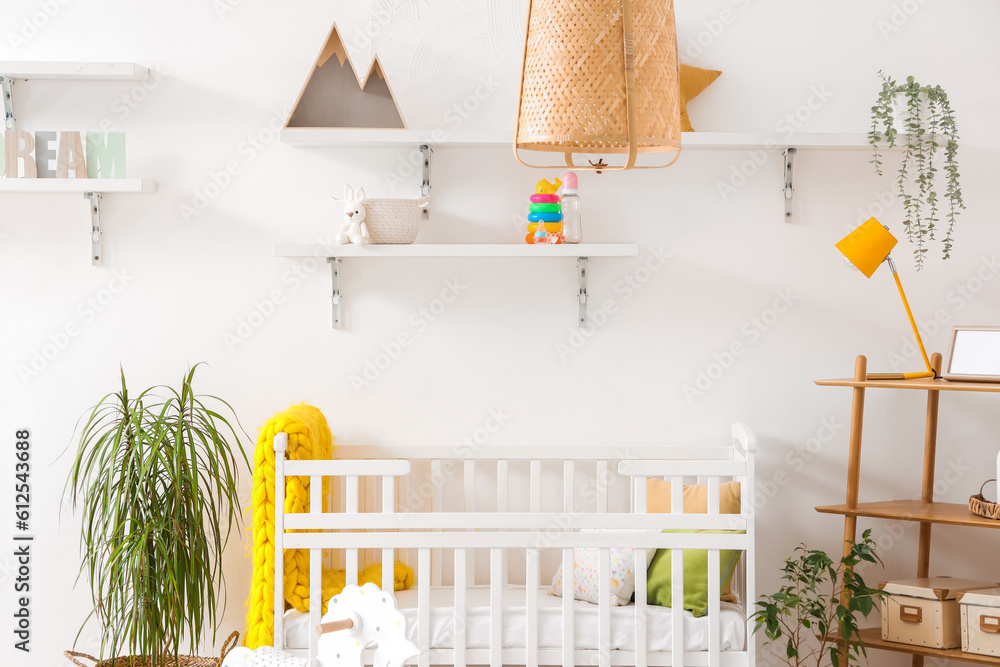 Stylish interior of childrens room with baby bed and rocking horse