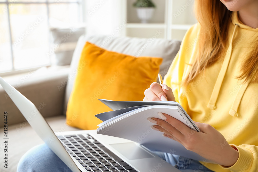 Female student studying with notebook and laptop at home, closeup