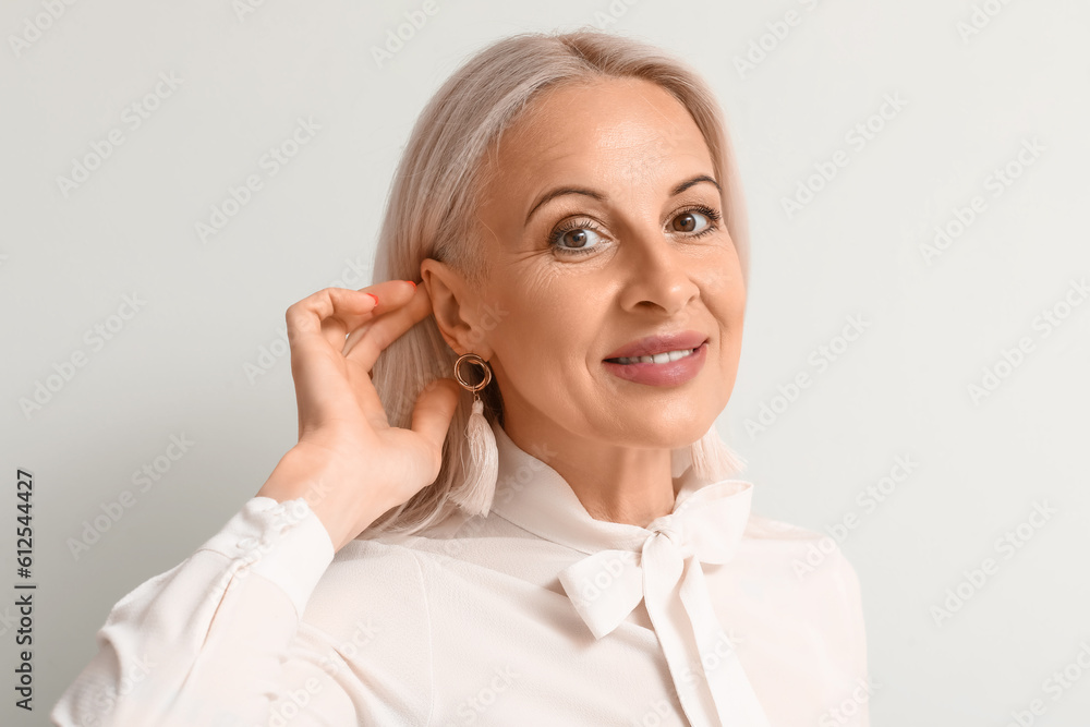 Mature blonde woman on light background, closeup