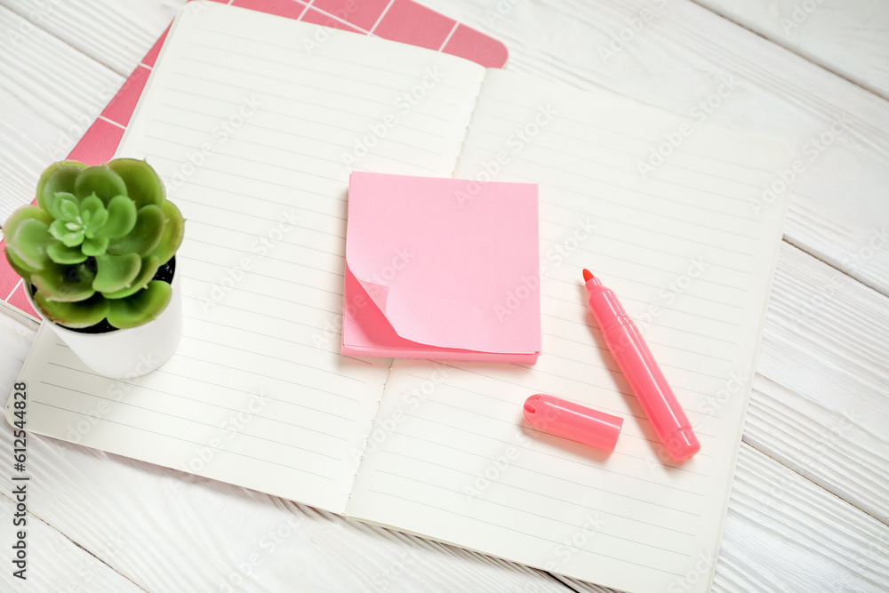 Sticky notes with notebooks on white wooden background