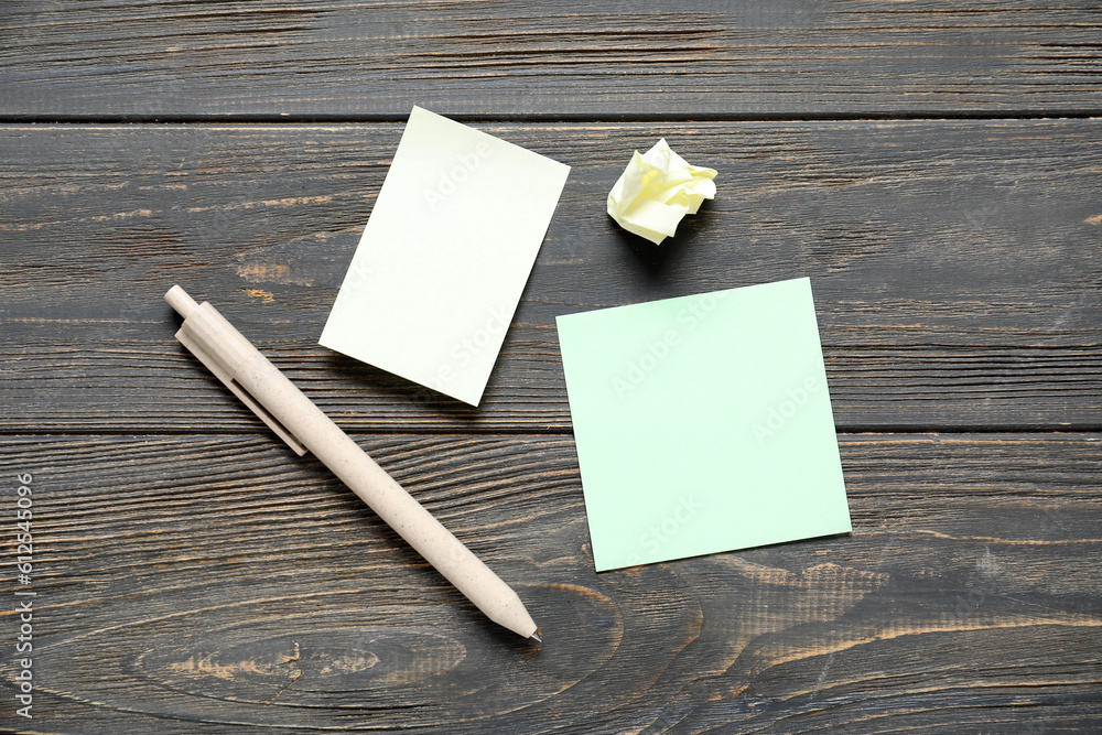 Sticky notes with pen on black wooden background