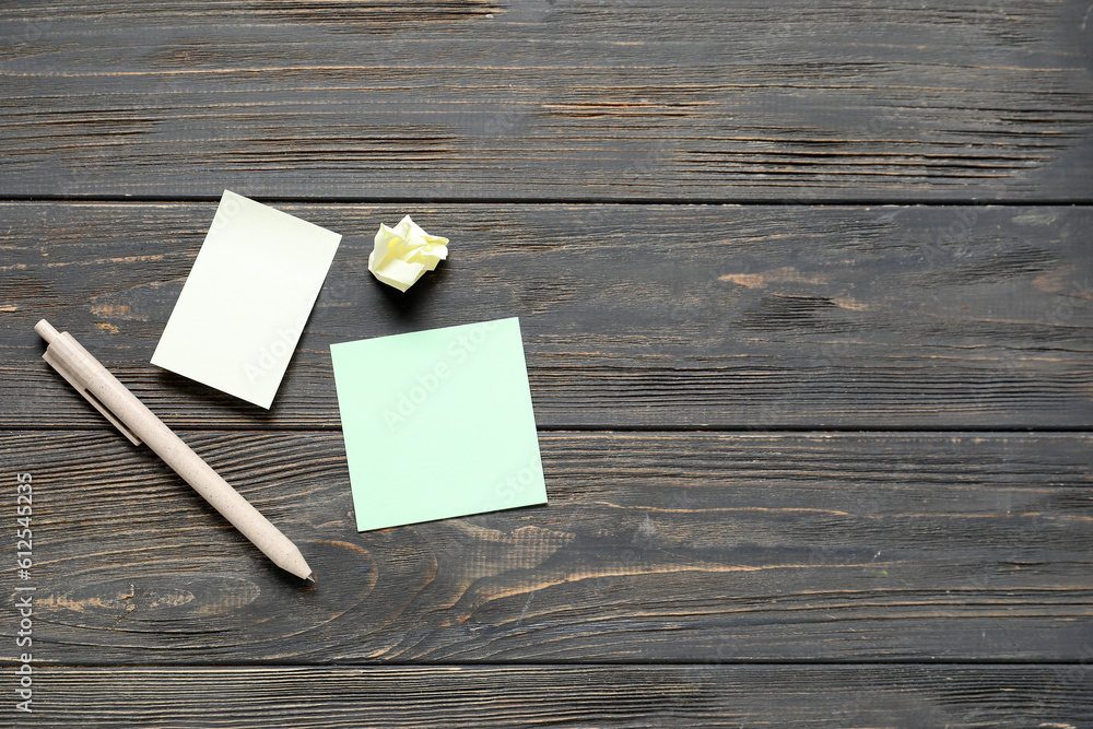 Sticky notes with pen on black wooden background