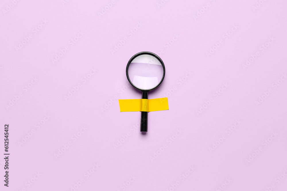 Magnifier with adhesive tape on lilac background