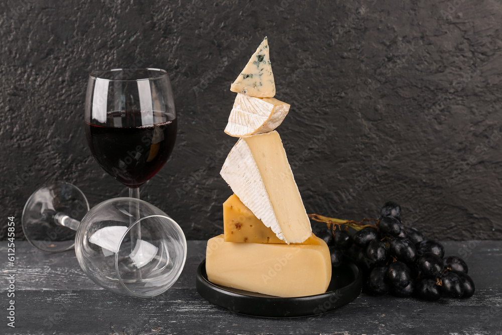 Different types of tasty cheese and glasses with wine on table