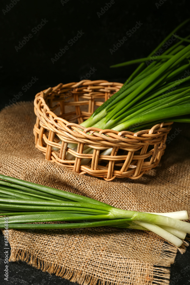 Wicker basket with fresh green onion on dark background